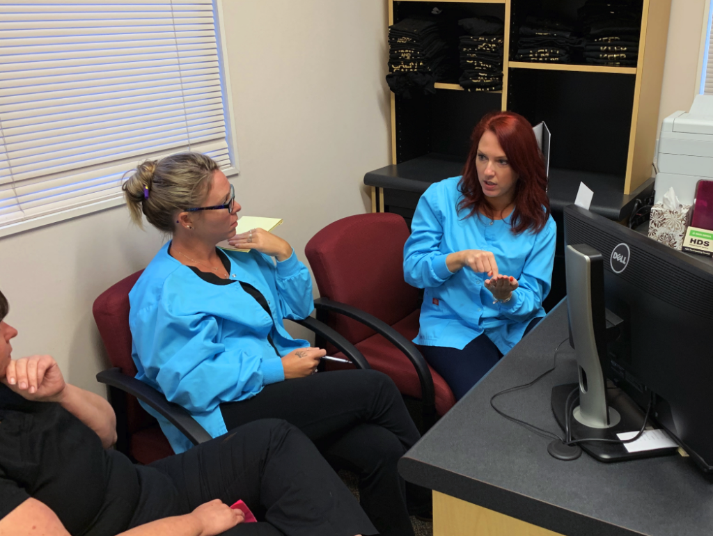 Three females sit and discuss details of treatment coordinator duties